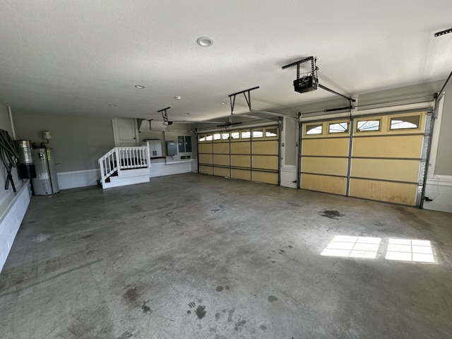 garage with a garage door opener, electric water heater, and electric panel