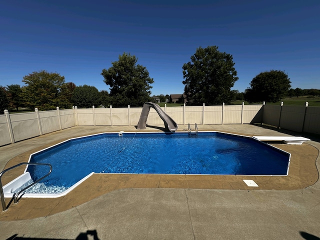 view of swimming pool with a patio, a water slide, and a diving board