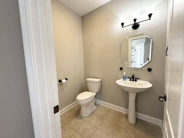 bathroom with toilet, sink, and tile patterned flooring