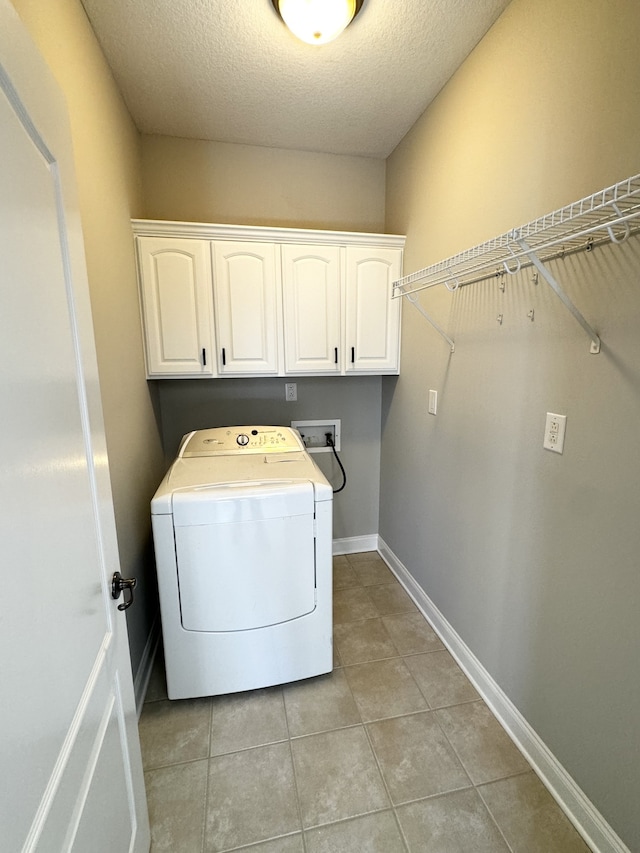 laundry room with light tile patterned flooring, a textured ceiling, cabinets, and washer / clothes dryer