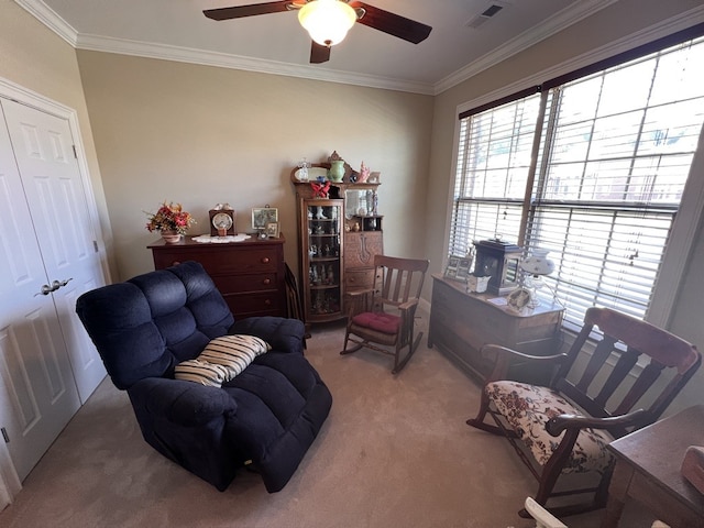 living area with ornamental molding, ceiling fan, and carpet floors