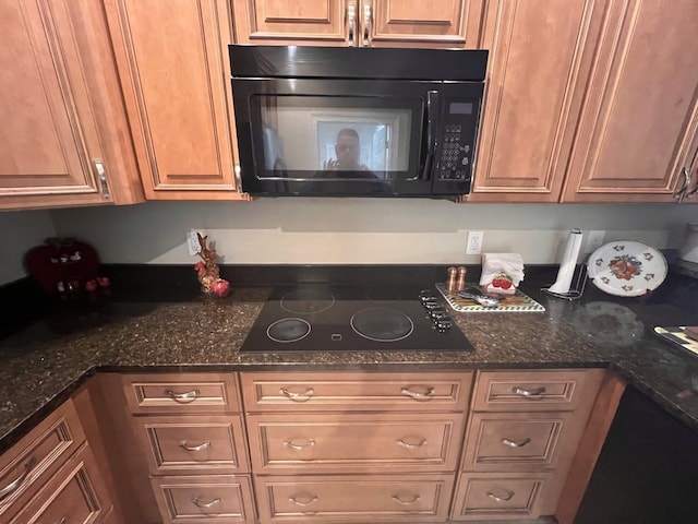 kitchen featuring dark stone countertops and black appliances