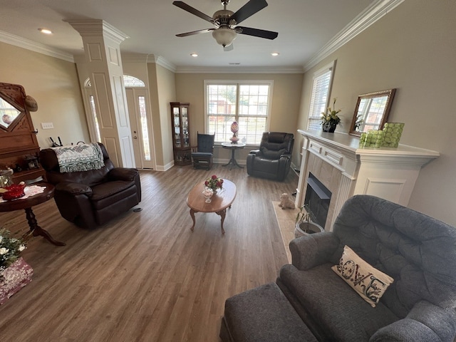 living room featuring ceiling fan, ornamental molding, wood-type flooring, and a tile fireplace