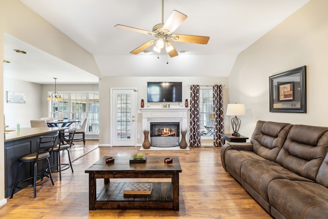 living room featuring ceiling fan with notable chandelier, vaulted ceiling, and hardwood / wood-style floors