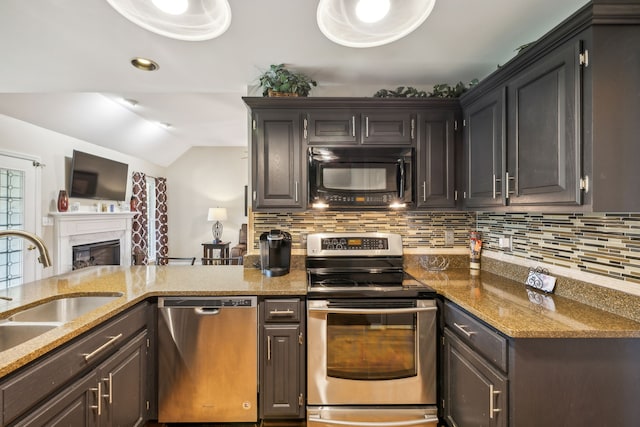 kitchen with sink, vaulted ceiling, appliances with stainless steel finishes, stone counters, and backsplash