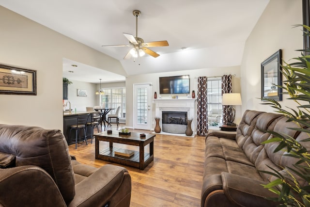 living room featuring sink, vaulted ceiling, light hardwood / wood-style flooring, and ceiling fan