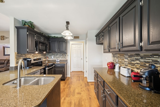 kitchen with pendant lighting, light hardwood / wood-style flooring, stainless steel stove, sink, and decorative backsplash