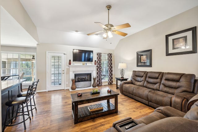 living room featuring hardwood / wood-style flooring, ceiling fan, and vaulted ceiling