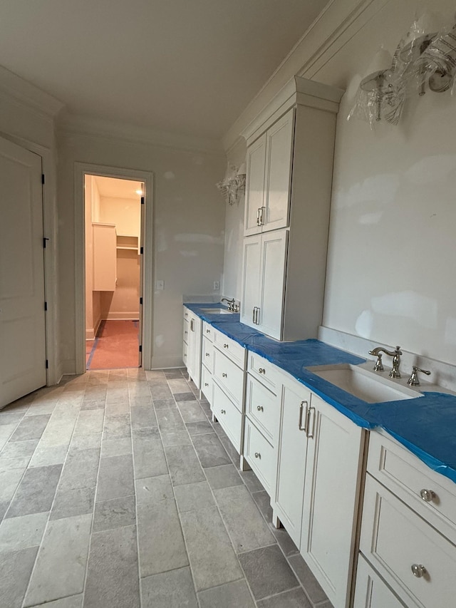 kitchen featuring sink, ornamental molding, and white cabinets