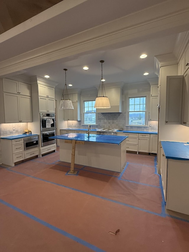 kitchen featuring white cabinets, a kitchen island, tasteful backsplash, and stainless steel appliances