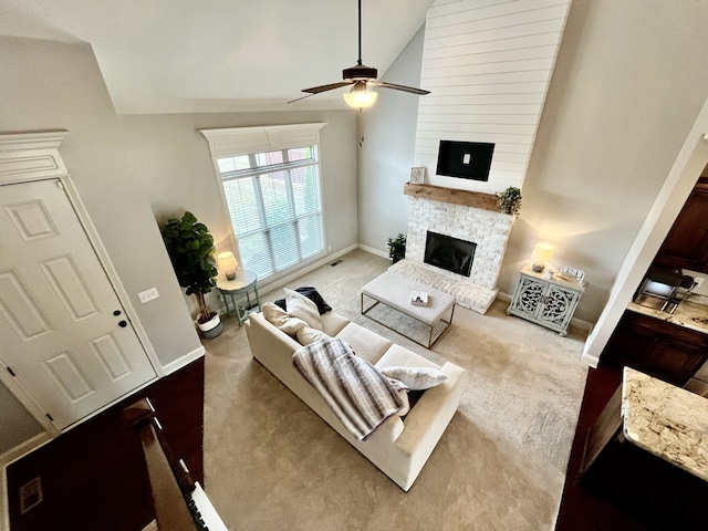 carpeted living room featuring a fireplace, high vaulted ceiling, and ceiling fan