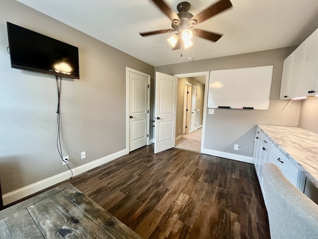 interior space with white cabinets, light stone countertops, dark hardwood / wood-style floors, and ceiling fan