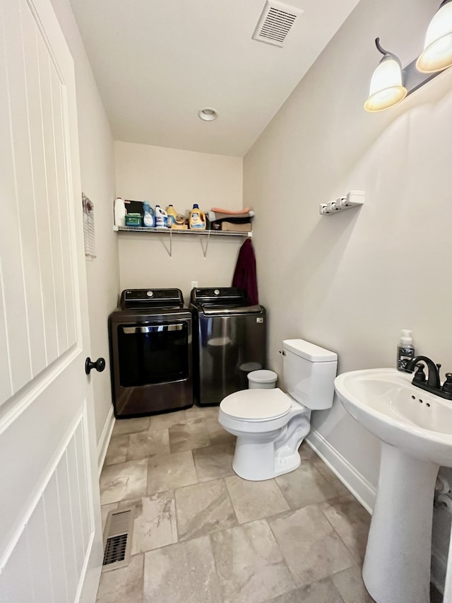 bathroom featuring separate washer and dryer and toilet