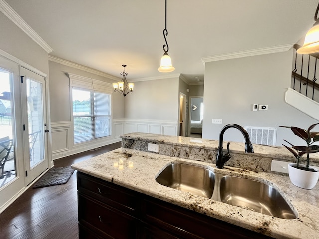 kitchen with light stone counters, sink, pendant lighting, and ornamental molding