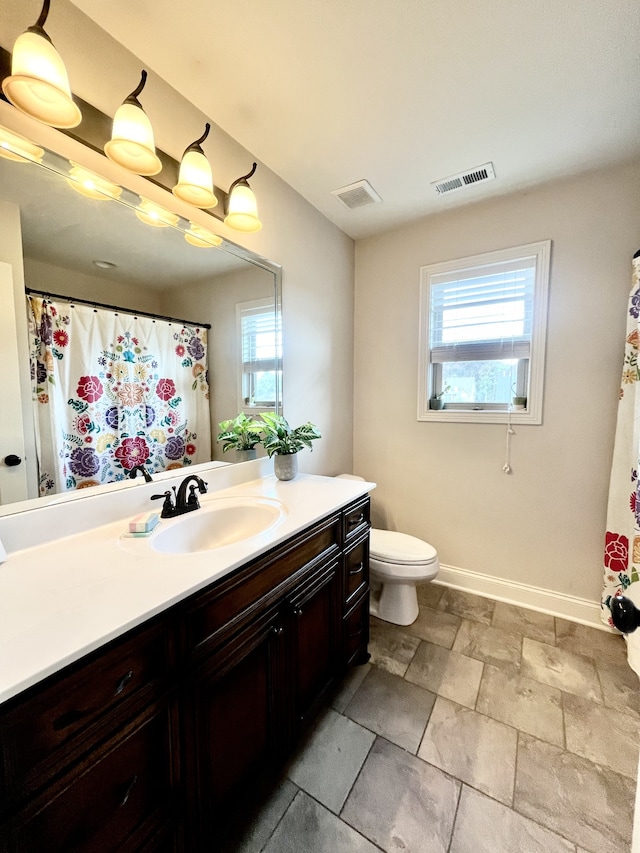 bathroom with plenty of natural light, toilet, and vanity