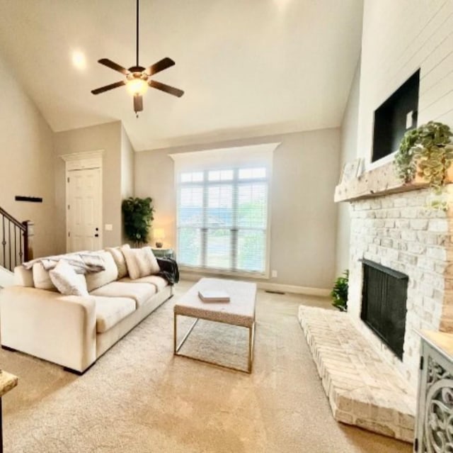 living room with ceiling fan, vaulted ceiling, carpet floors, and a brick fireplace