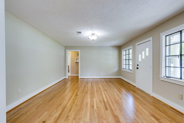 foyer with light wood-type flooring, a healthy amount of sunlight, and a textured ceiling