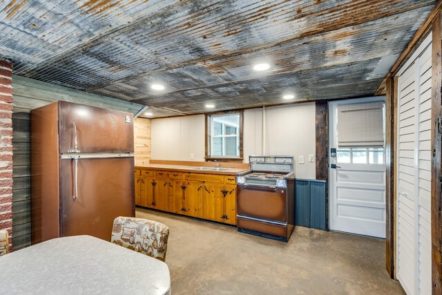 kitchen featuring wood walls, stove, and sink