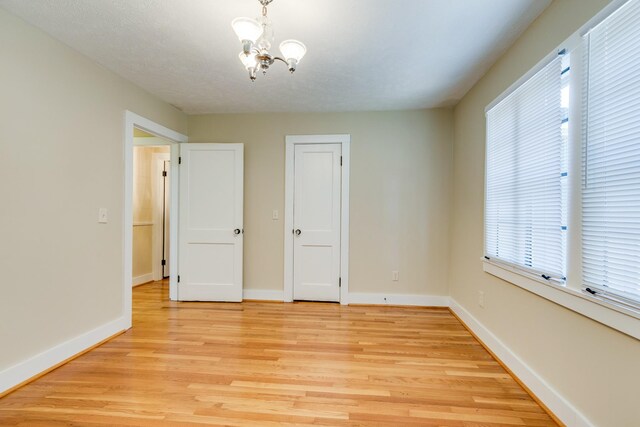 interior space featuring an inviting chandelier, light hardwood / wood-style flooring, and a textured ceiling