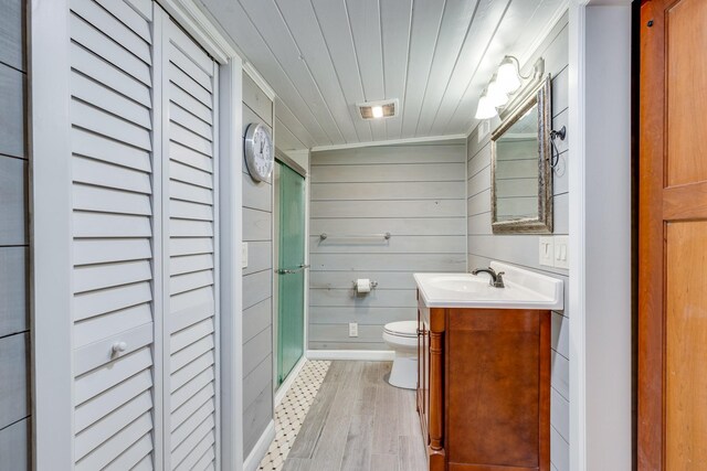 bathroom featuring wood-type flooring, vaulted ceiling, walk in shower, vanity, and toilet