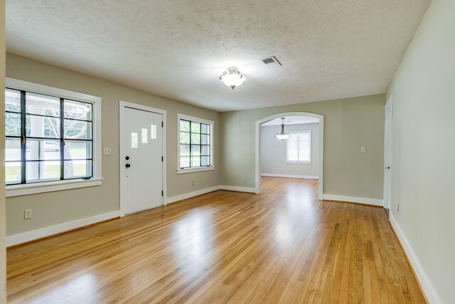 foyer entrance with a textured ceiling, light hardwood / wood-style floors, and plenty of natural light