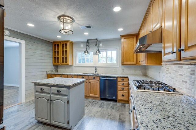 kitchen featuring light stone counters, a kitchen island, appliances with stainless steel finishes, a notable chandelier, and light wood-type flooring