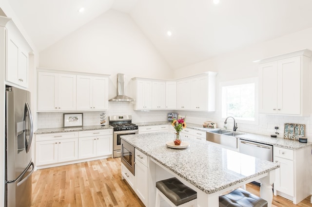 kitchen featuring appliances with stainless steel finishes, white cabinetry, wall chimney range hood, and tasteful backsplash