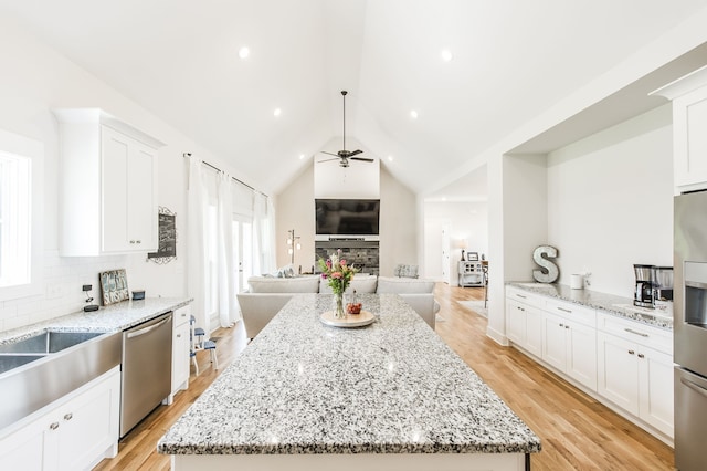 kitchen featuring light hardwood / wood-style floors, ceiling fan, a center island, and a fireplace