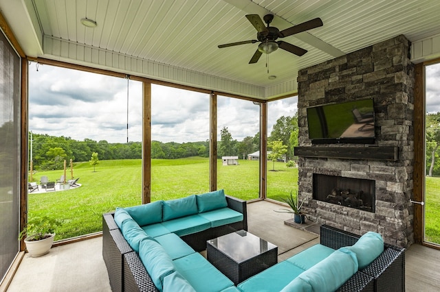 sunroom / solarium with ceiling fan and an outdoor stone fireplace