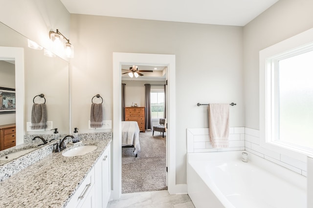 bathroom featuring ceiling fan, vanity, and a tub to relax in