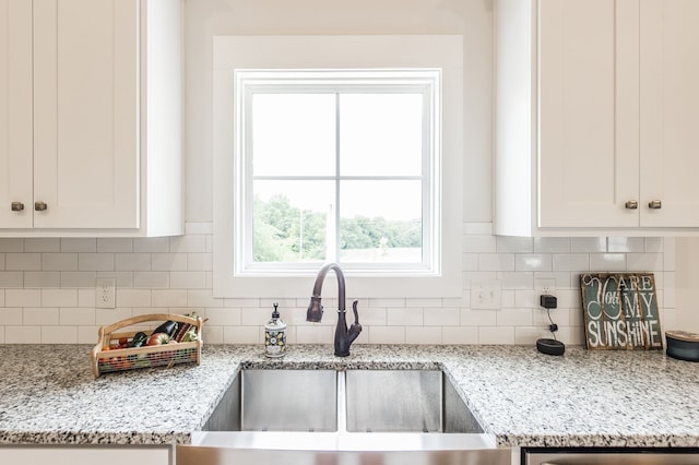 kitchen with light stone countertops, sink, and white cabinetry