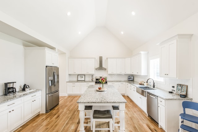 kitchen with light hardwood / wood-style floors, sink, white cabinetry, wall chimney range hood, and stainless steel appliances