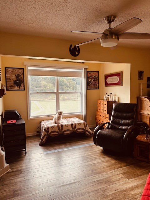 living room with ceiling fan, a textured ceiling, and hardwood / wood-style floors