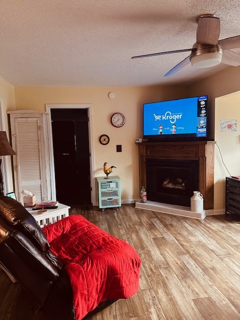 living room featuring ceiling fan, hardwood / wood-style flooring, and a textured ceiling