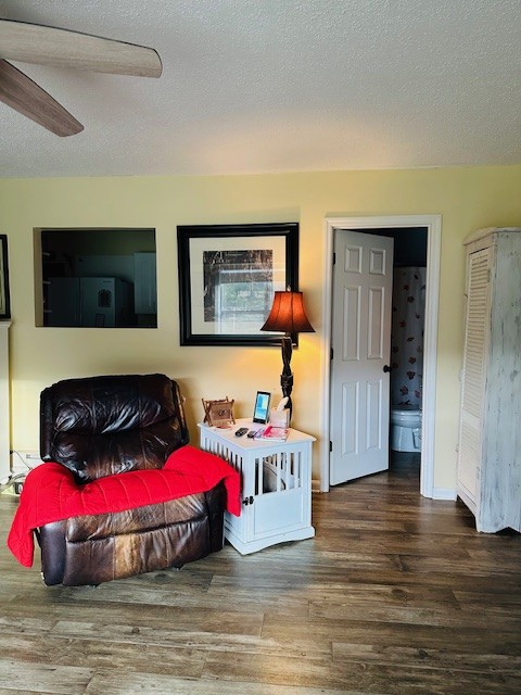 sitting room featuring wood-type flooring, a textured ceiling, and ceiling fan