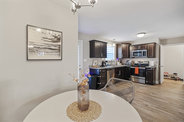 kitchen with dark brown cabinetry, sink, light hardwood / wood-style flooring, appliances with stainless steel finishes, and light stone countertops