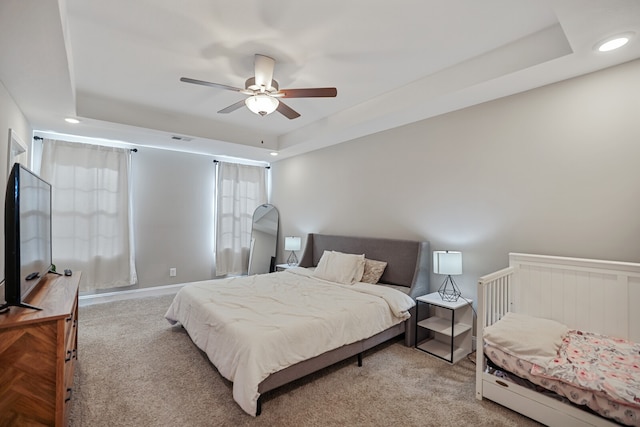 bedroom with carpet, a tray ceiling, and ceiling fan