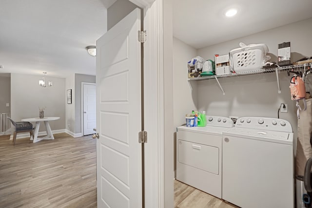 laundry room with an inviting chandelier, light hardwood / wood-style floors, and washer and dryer