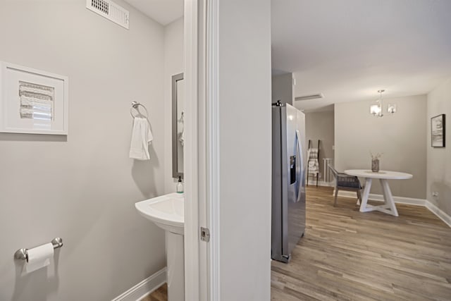 bathroom with wood-type flooring and a chandelier