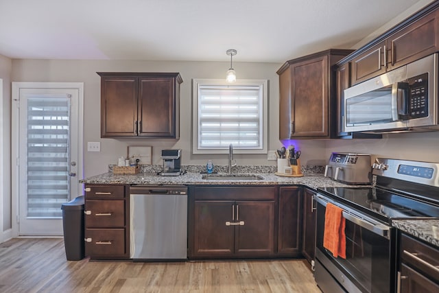 kitchen featuring light hardwood / wood-style flooring, light stone counters, appliances with stainless steel finishes, and sink