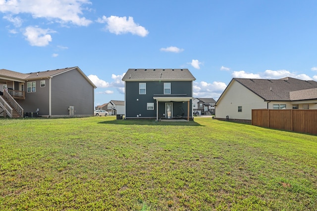 rear view of house with a lawn and central AC unit