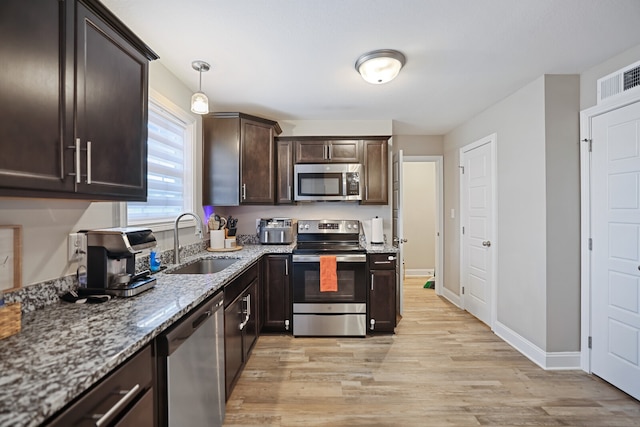 kitchen featuring light hardwood / wood-style floors, light stone countertops, stainless steel appliances, and decorative light fixtures