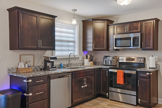 kitchen featuring light stone countertops, stainless steel appliances, light wood-type flooring, and sink