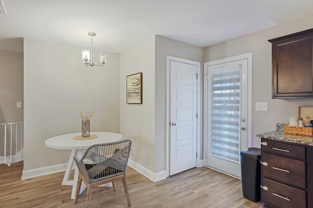 dining room with light wood-type flooring and a notable chandelier