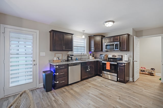 kitchen featuring sink, hanging light fixtures, light hardwood / wood-style flooring, appliances with stainless steel finishes, and dark brown cabinetry