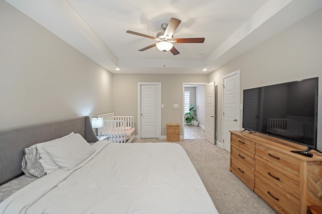 carpeted bedroom with a tray ceiling and ceiling fan