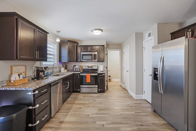 kitchen featuring pendant lighting, light wood-type flooring, sink, appliances with stainless steel finishes, and light stone countertops