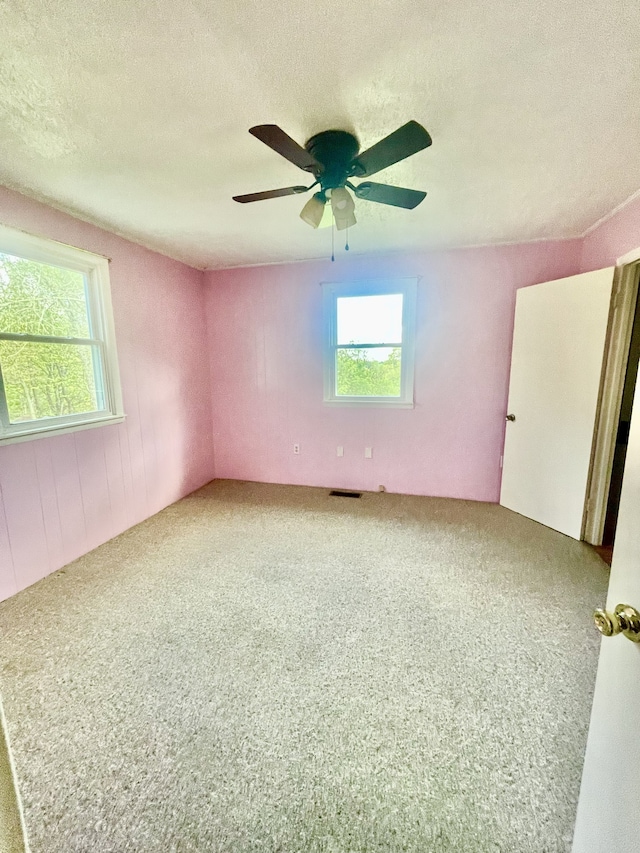 empty room featuring a textured ceiling, ceiling fan, and carpet floors