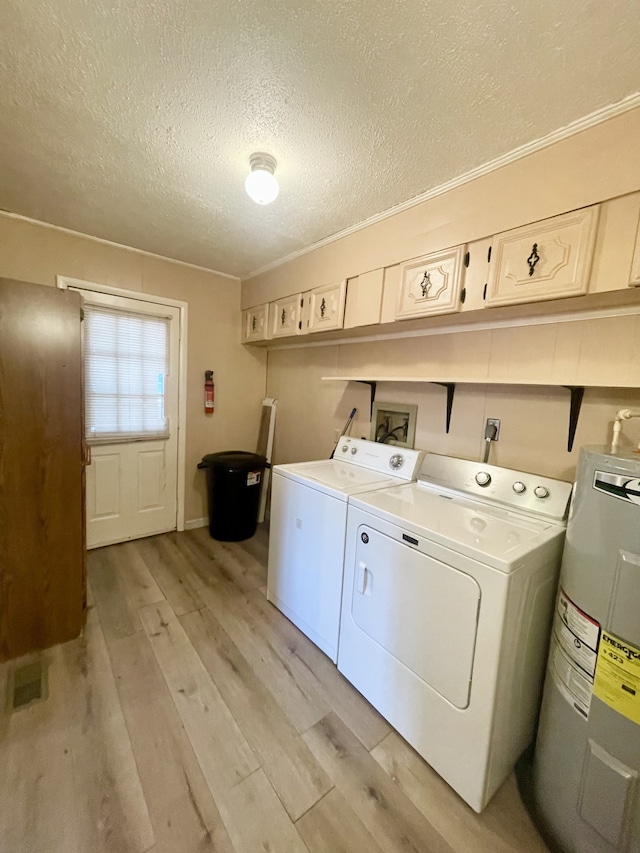 laundry room featuring electric water heater, light wood-type flooring, a textured ceiling, cabinets, and washing machine and clothes dryer