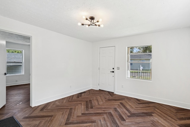 entryway with a textured ceiling, dark parquet floors, and a notable chandelier